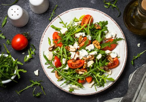 Arugula salad with tomatoes and blue cheese at black. Arugula salad with tomatoes and blue cheese at black.